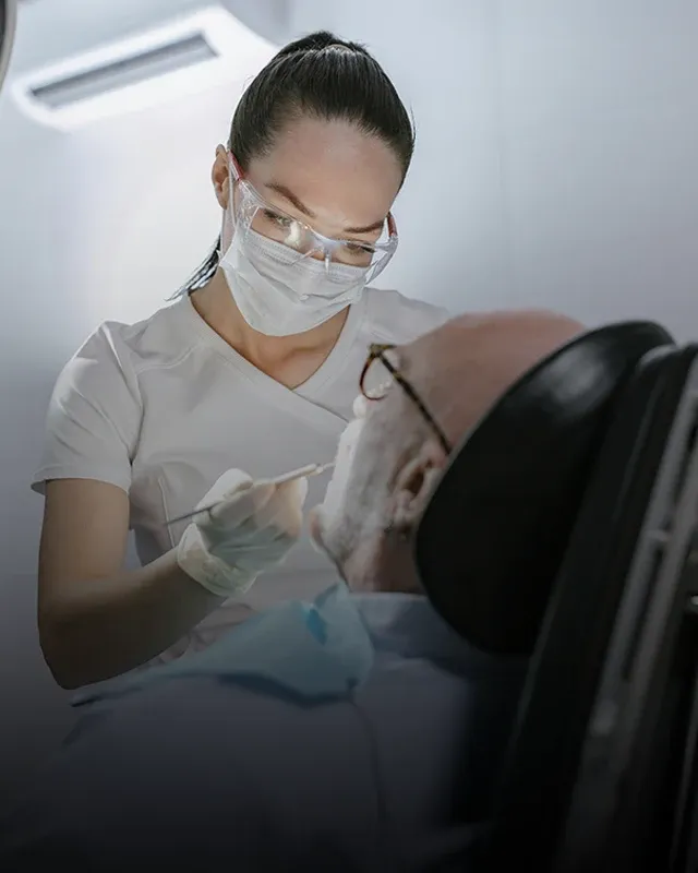 A dental professional performing a cleaning of a patient's teeth