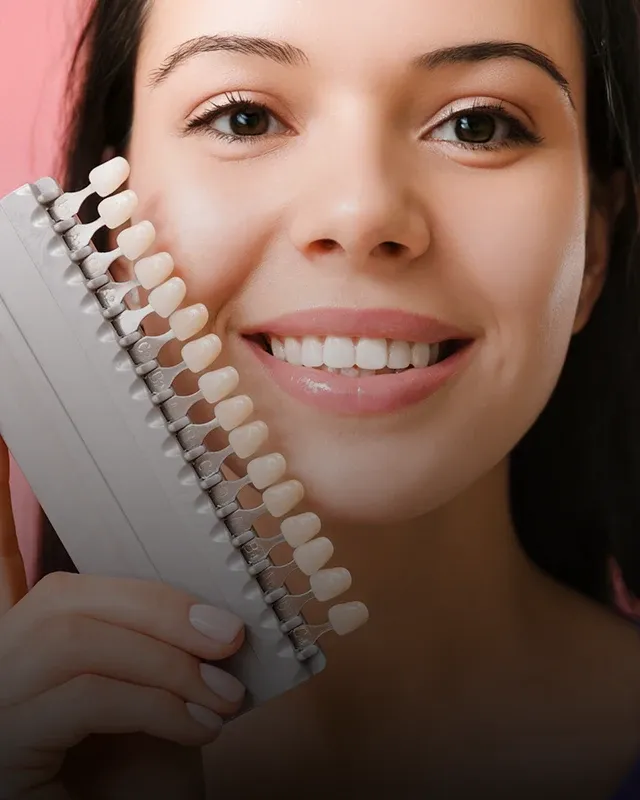 A woman holding tooth color shade selector up to her face